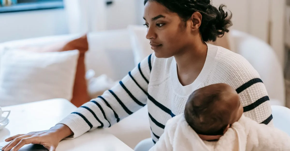Mère multitâchant entre le travail et la garde d'enfants, utilisant un ordinateur portable, embrassant la parentalité.
