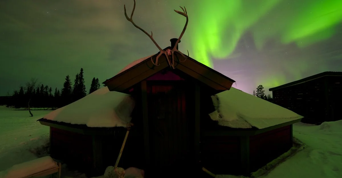 Belles Aurores Boréales au-dessus d'une cabane enneigée et d'une forêt à Kiruna, Suède.