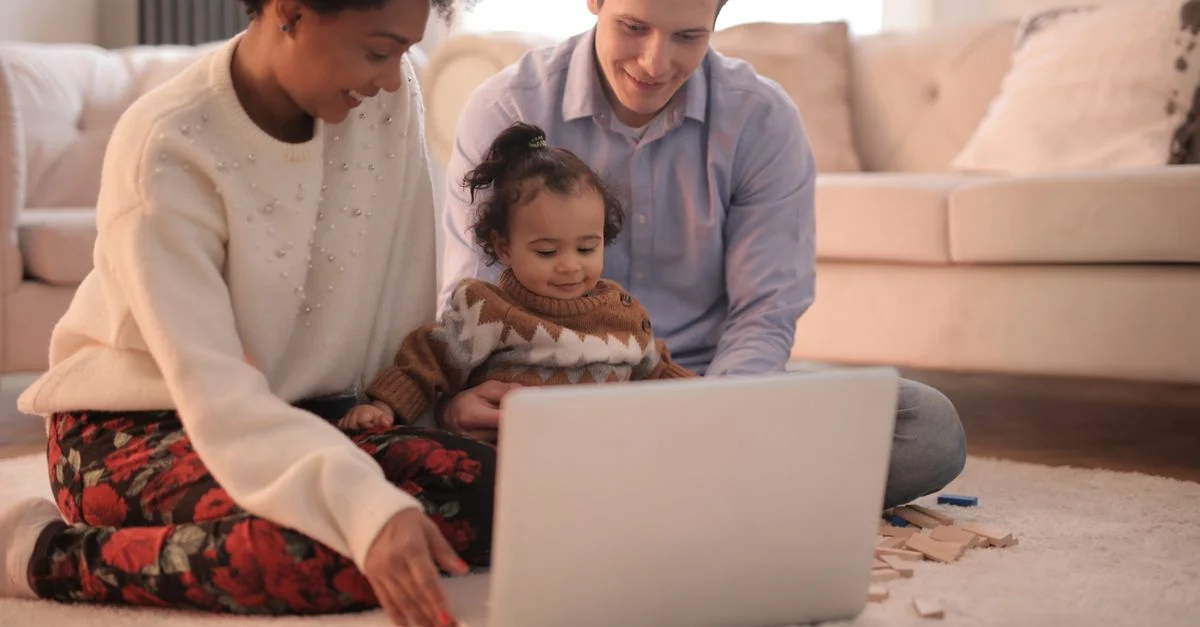 Une famille joyeuse de trois personnes se liant ensemble en utilisant un ordinateur portable dans un cadre de salon confortable.