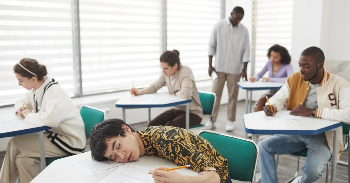 Des étudiants dans une salle de classe passant un examen, montrant diversité et concentration.