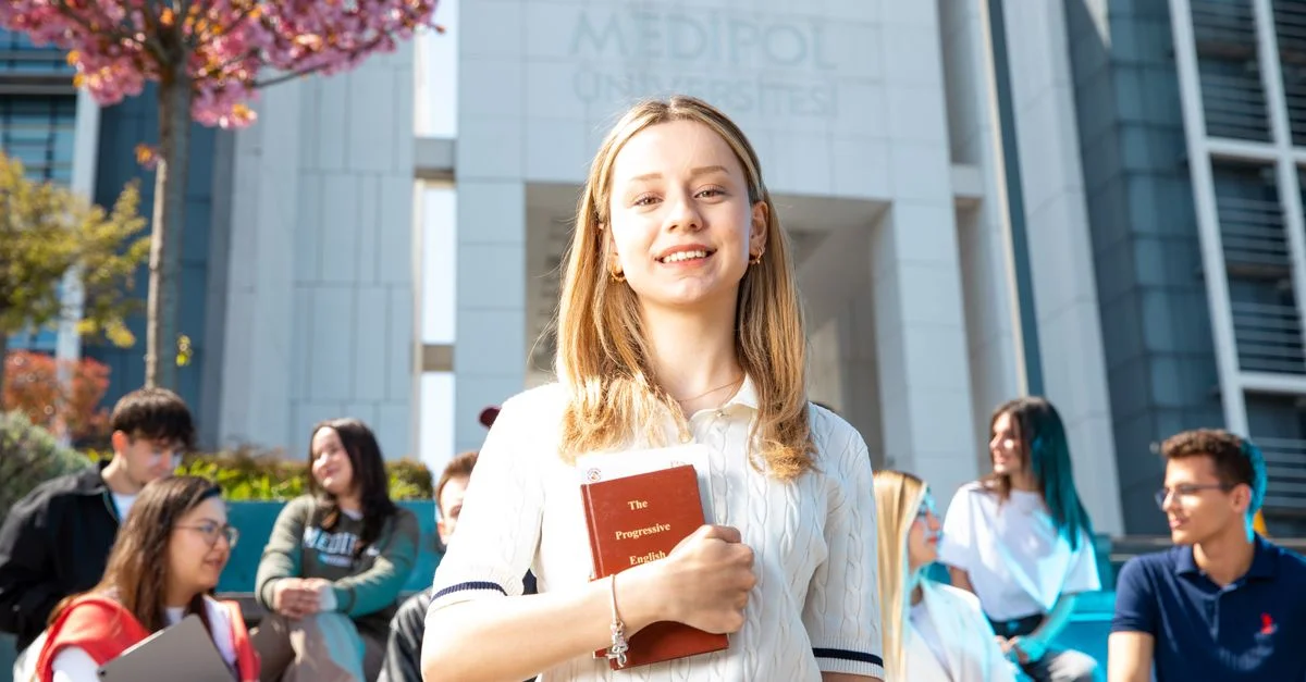 Des étudiants universitaires heureux socialisent sur le campus, avec un focus sur une jeune femme souriante tenant un livre.