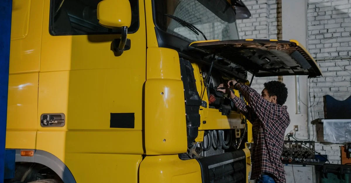 Un mécanicien travaillant sur le moteur d'un camion dans un atelier mécanique intérieur.