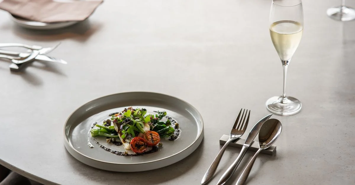 Une table raffinée avec un plat gastronomique et une coupe de champagne dans un luxueux restaurant de Tokyo.