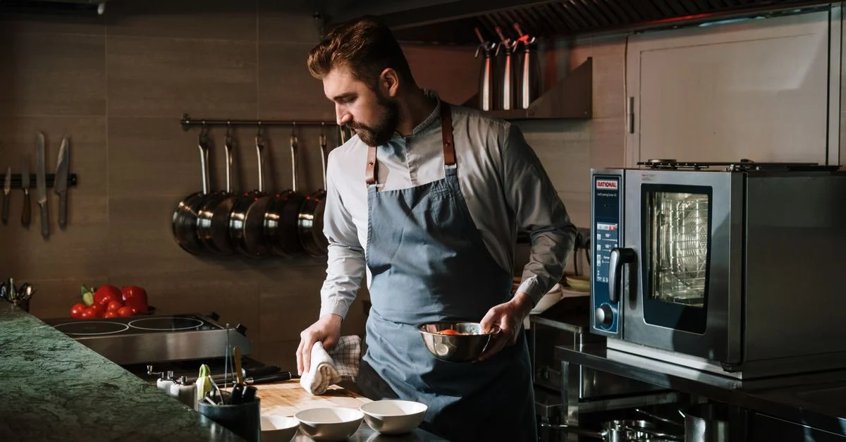 Chef masculin dans une cuisine de restaurant préparant un plat, mettant en valeur ses compétences et son expertise culinaires.