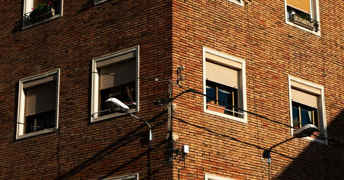 Le coin d'un bâtiment en briques rouges avec des fenêtres et des ombres, capturant l'architecture urbaine.
