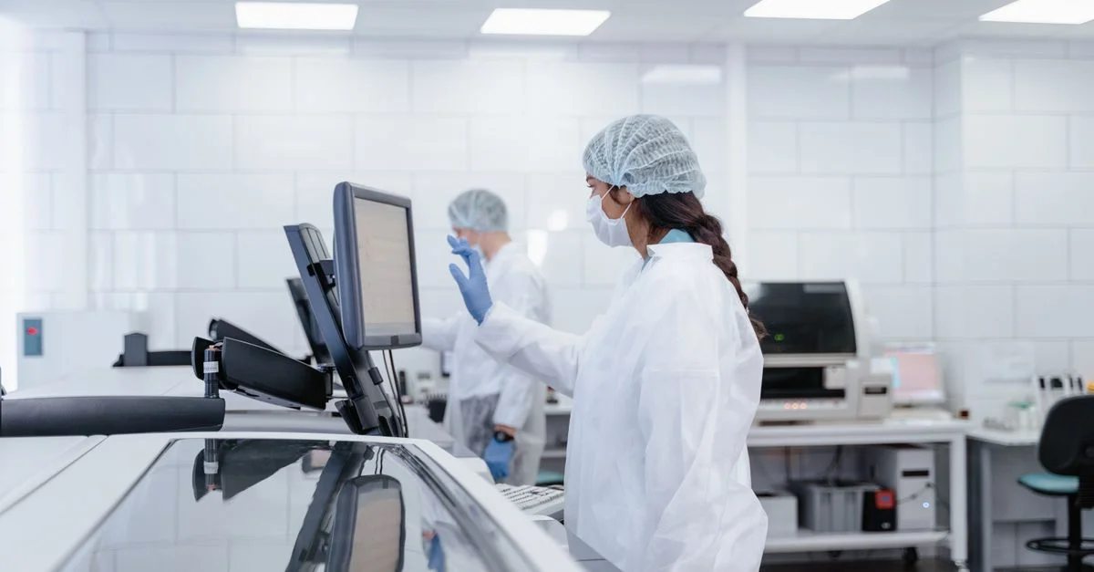 Une scientifique en tenue de protection utilise un équipement dans un laboratoire moderne.